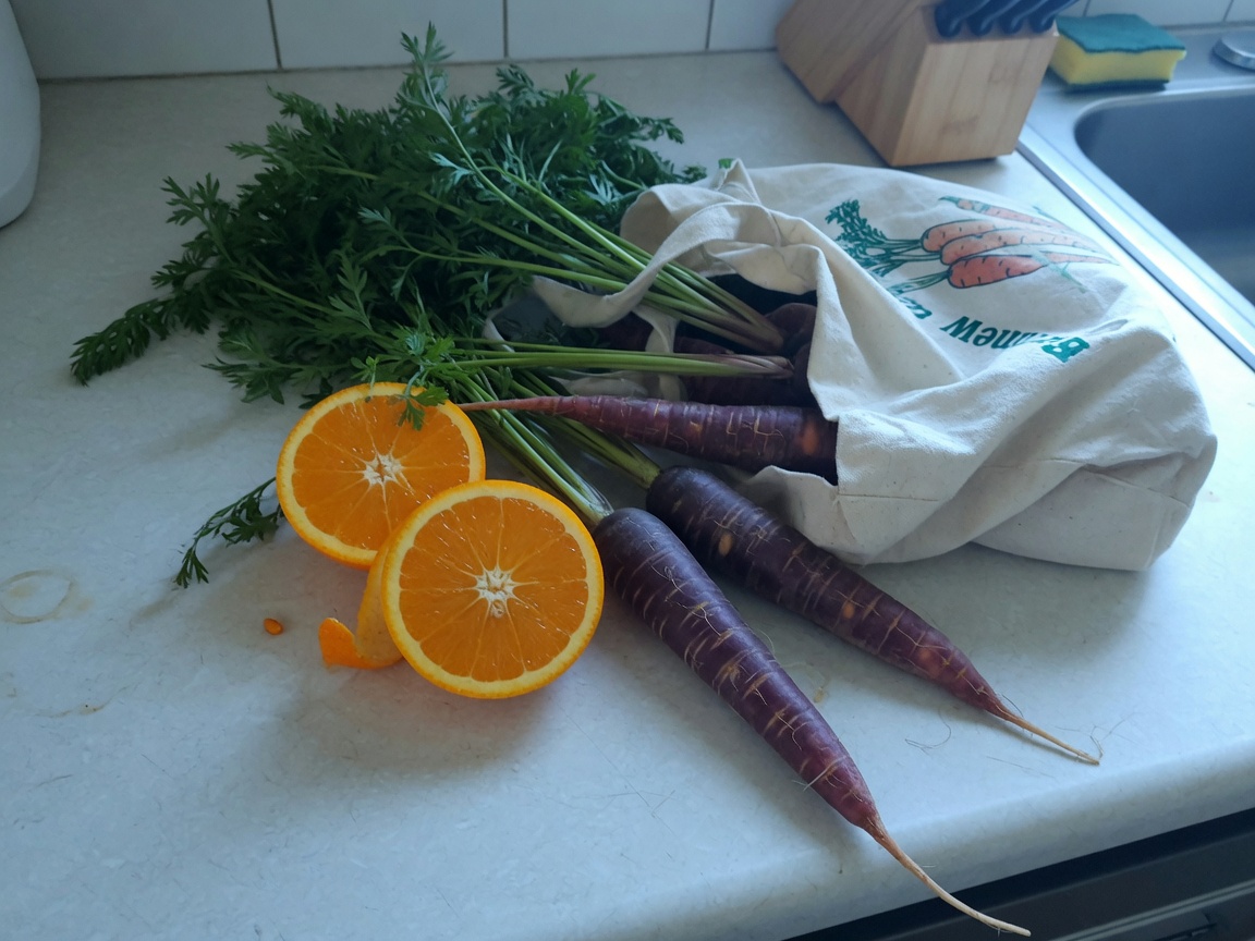 Purple carrots next to halved oranges